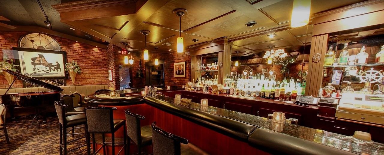 The warm, candlelit bar at Mr. Paul's Chophouse, brick walls and back-bar bottles glowing amber.
